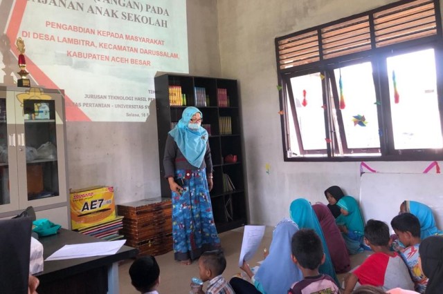 Dosen Universitas Syiah Kuala (USK) Banda Aceh mengajari anak-anak usia sekolah di Desa Lambitra, Kabupaten Aceh Besar, untuk mengenal jajanan sehat. Foto: Kiriman Asmawati