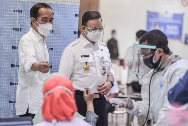 Presiden Joko Widodo (kiri) didampingi Gubernur DKI Jakarta Anies Baswedan (kedua kiri) meninjau vaksinasi COVID-19 massal bagi pedagang di Pasar Tanah Abang Blok A, Jakarta, Rabu (17/2/2021). Foto: Hafidz Mubarak A/ANTARA FOTO