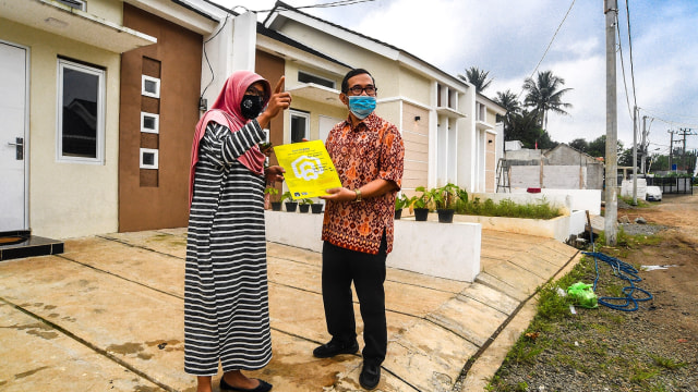 Petugas pemasaran perumahan menyerahkan dokumen Kredit Pemilikan Rumah (KPR) kepada pembeli di Perumahan Taman Harapan, Tajur Halang, Bogor, Jawa Barat, Rabu (17/2/2021). Foto: Muhammad Adimaja/ANTARA FOTO