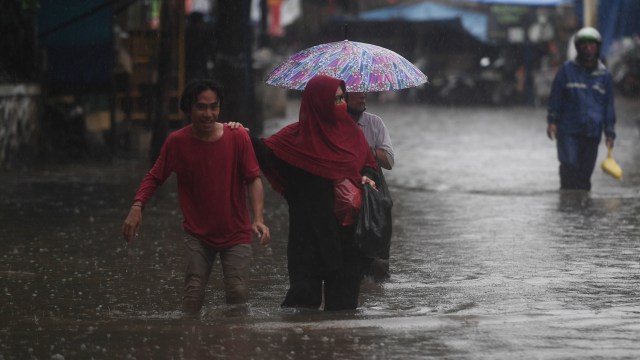 Warga berjalan melintasi banjir yang merendam kawasan RW 5, Duren Tiga, Pancoran, Jakarta, Kamis (18/2/2021). Foto: Akbar Nugroho Gumay/ANTARA FOTO