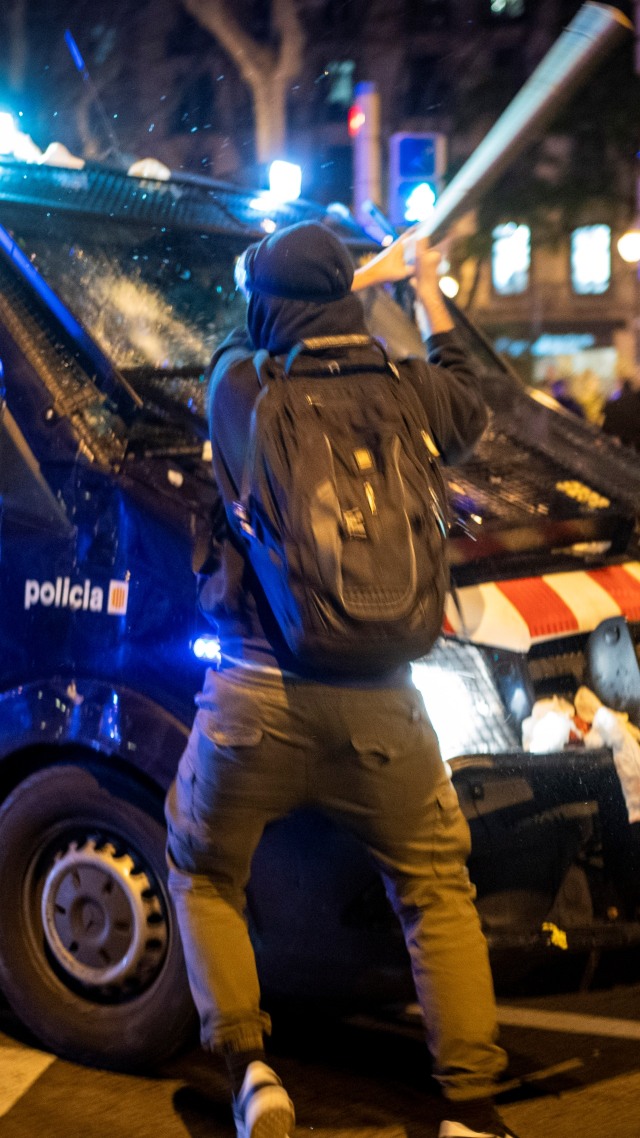 Seorang demonstran memukul van polisi dengan tongkat saat bentrokan pada aksi protes penangkapan rapper Catalan Pablo Hasel, di Barcelona, Spanyol, Rabu (17/2). Foto: Emilio Morenatti/AP Photo