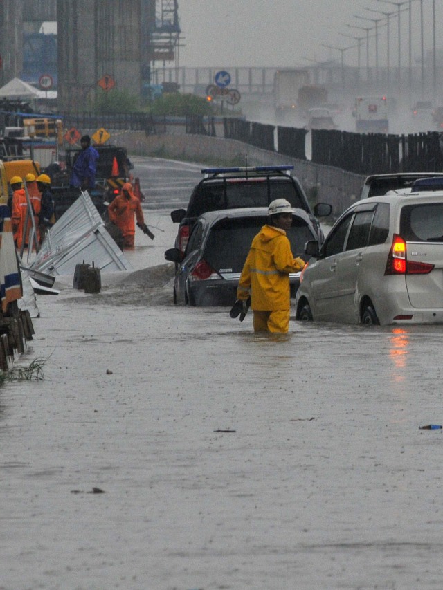 Petugas mengatur kendaraan yang melintasi banjir di gerbang tol Jakarta-Cikampek, di Jatibening, Bekasi, Jawa Barat, Jumat (19/2). Foto: Fakhri Hermansyah/Antara Foto