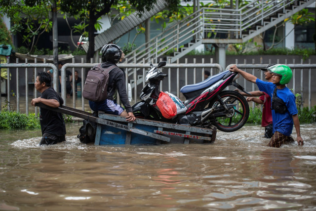 Warga mengangkut sepeda motor menggunakan gerobak melintasi banjir di Jalan Kapten Tendean, Mampang Prapatan, Jakarta, Sabtu (20/2).  Foto: Aprillio Akbar/ANTARA FOTO