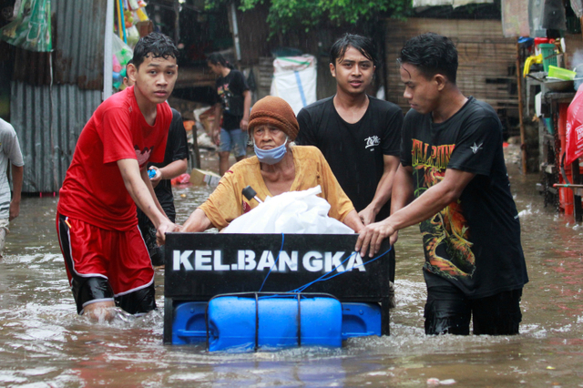 Pemuda mengangkut seorang wanita lanjut usia menggunakan rakit darurat di daerah yang terkena banjir menyusul hujan lebat di Jakarta. Foto: REUTERS / Ajeng Dinar Ulfiana