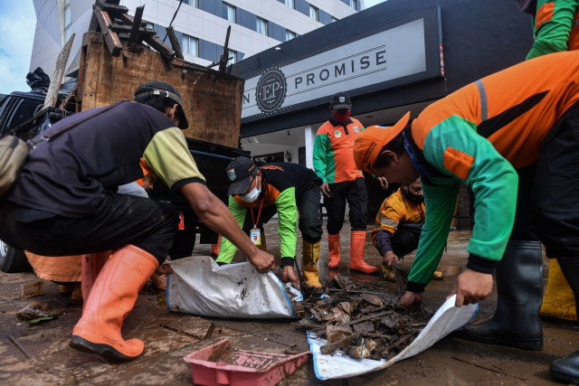 Petugas membersihkan sisa-sisa sampah pasca banjir di kawasan Kemang, Jakarta Selatan, Minggu (21/2/2021). Foto: Sigid Kurniawan/ANTARA FOTO