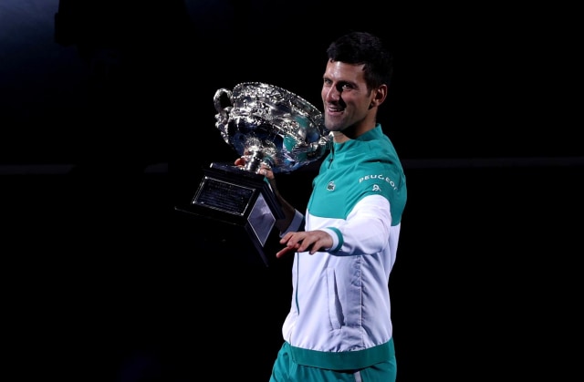 Petenis Novak Djokovic dari Serbia membawa trofi  Australian Open 2021 usai melawan petenis Rusia Daniil Medvedev. Foto: Loren Elliott/Reuters