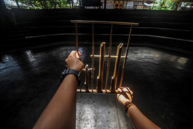 Seorang instruktur memegang angklung di aula pementasan yang kosong di Saung Angklung Udjo. Foto: Raisan Al Farisi/ANTARA FOTO