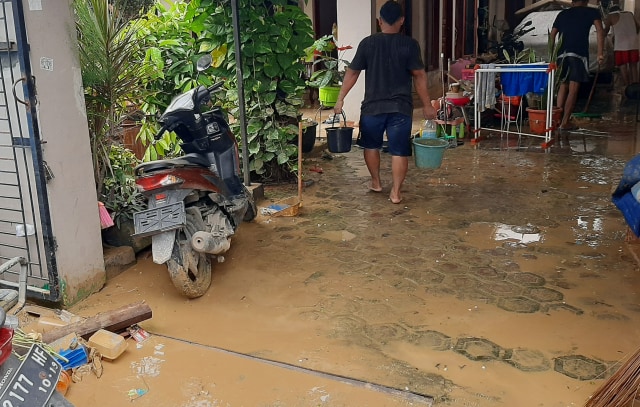 Warga sedang membersihkan lumpur akibat banjir