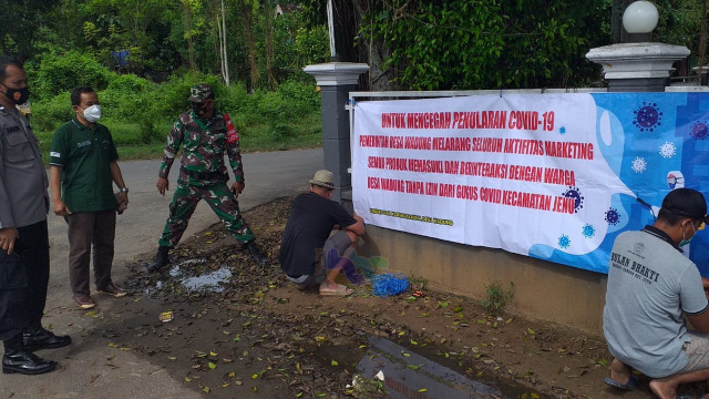 Warga Desa Wadung, Kecamatan Jenu, Kabupaten Tuban, saat memasang spanduk atau banner larangan terhadap aktivitas sales dan marketing. (foto: ayu/beritabojonegoro)