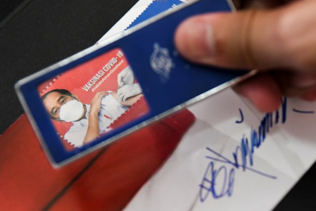 Petugas menunjukkan sampul hari pertama perangko edisi vaksinasi nasional COVID-19 di Kantor Filateli, Jakarta, Jumat (26/2).  Foto: Galih Pradipta/ANTARA FOTO