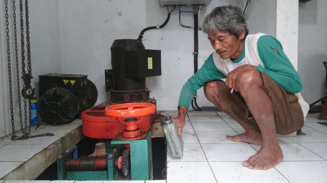 Rejo Handoyo sedang menuang oli ke dalam generator mikro hidro. Foto: Widi Erha Pradana. 
