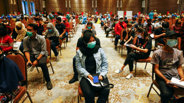 Orang-orang yang memakai masker pelindung duduk mengantre sebelum mengikuti vaksinasi COVID-19 massal tahap kedua di Mal Tangerang City, Tangerang, Banten, Senin (1/3/2021). Foto: Ajeng Dinar Ulfiana/REUTERS