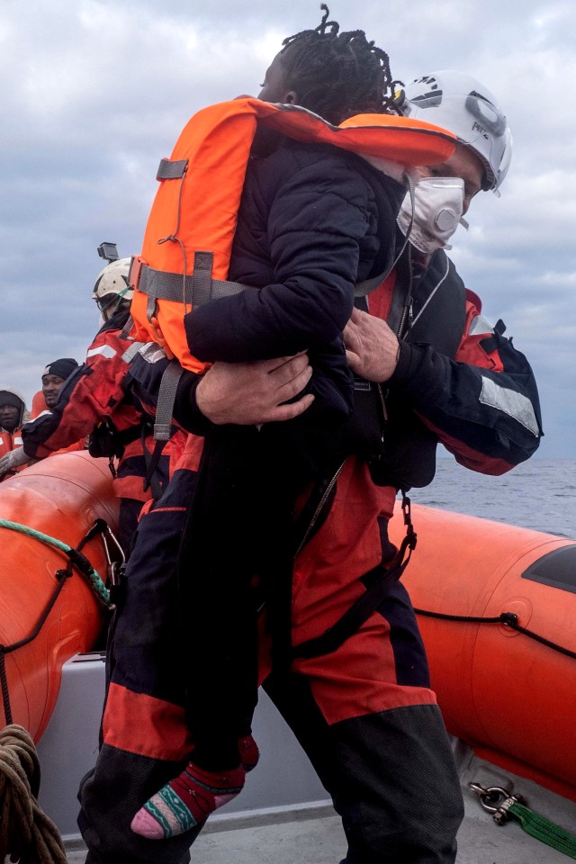 Seorang anggota tim kapal penyelamat Sea-Watch Jerman membantu seorang migran anak-anak naik perahu selama operasi penyelamatan di Laut Mediterania, Jumat (26/2). Foto: Sea-Watch/Handout via REUTERS