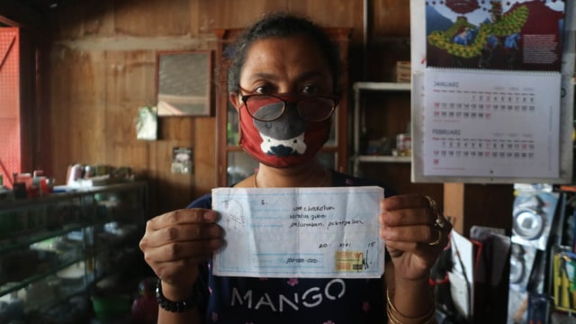 Kusmiyati, seorang ibu di Grobogan Jawa Tengah memegang kwitansi pembayaran 'uang pelicin' agar anakya masuk jadi PNS. Foto: kumparan