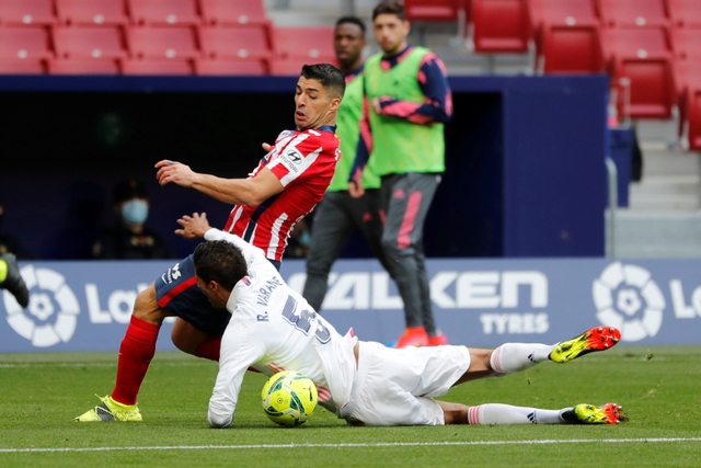 Pemain Atletico Madrid Luis Suarez berebut bola dengan pemain Real Madrid Raphael Varane pada pertandingan lanjutan Liga Spanyol di Wanda Metropolitano, Madrid, Spanyol. Foto: Susana Vera/REUTERS