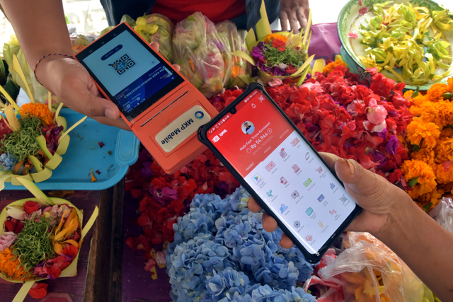 Pedagang di pasar Singaraja Bali sedang melakukan pembayaran e-retribusi menggunakan DOKU e-Wallet dengan fitur scan QRIS - IST