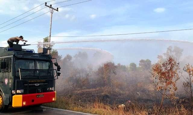 Personel Polres Karimun mendinginkan lahan yang terbakar menggunakan Water Canon. (Foto: ist)