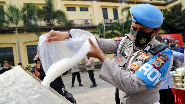 Seorang personel kepolisian memasukkan barang bukti narkotika jenis sabu-sabu ke mesin molen untuk dimusnahkan di lapangan Mapolda Aceh, Rabu (10/3). Foto: Suparta/acehkini