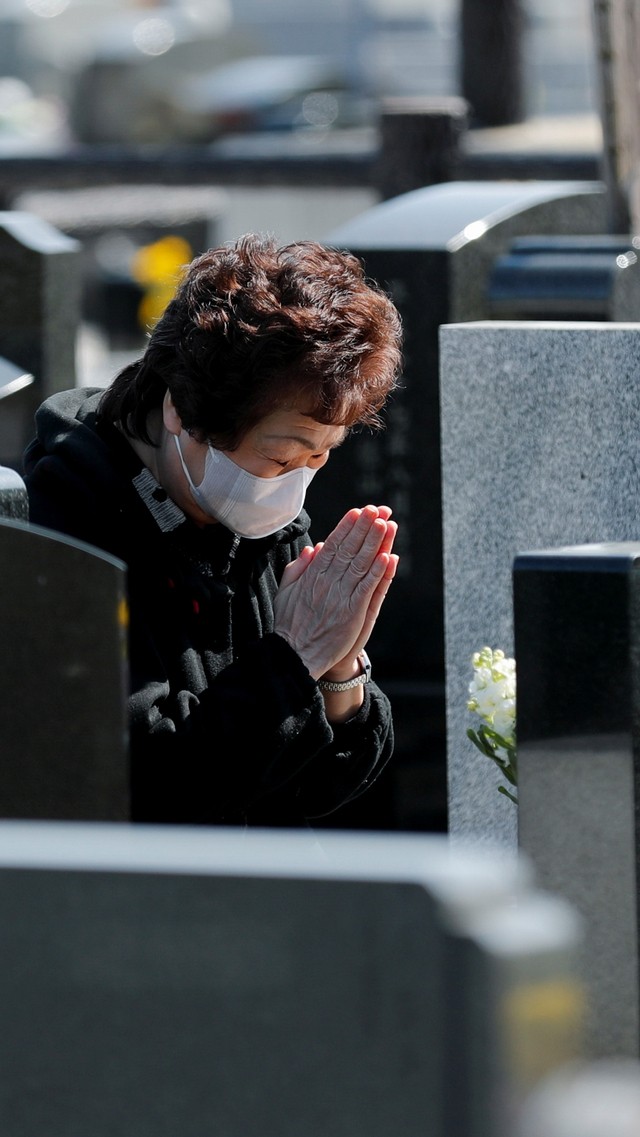 Seorang wanita berdoa untuk anggota keluarga yang meninggal pada tsunami 2011, di pemakaman di Namie, prefektur Fukushima, Jepang, Kamis (11/3). Foto: Kim Kyung-Hoon/REUTERS