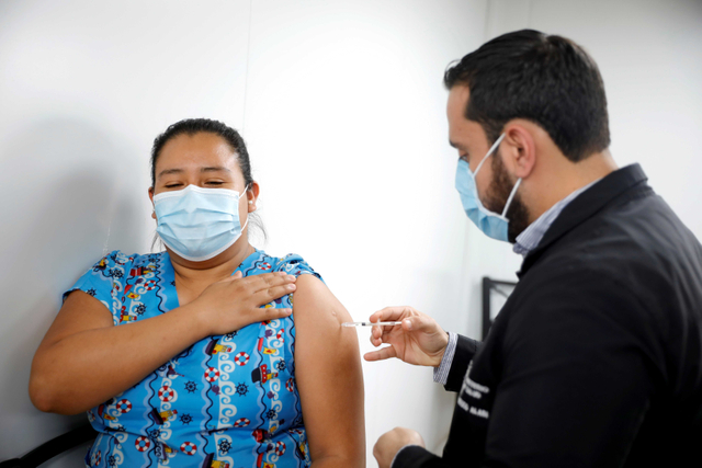 Seorang petugas kesehatan menerima dosis vaksin AstraZeneca (SKBio Corea) dari Menteri Kesehatan El Salvador Francisco Alabi, di sebuah pusat kesehatan umum. Foto: Jose Cabezas/Reuters