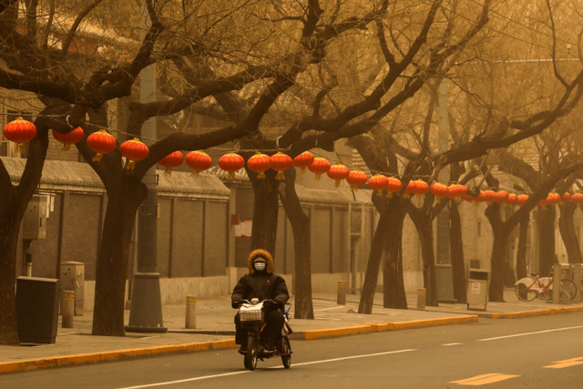 Seorang warga mengendarai sepeda listrik saat badai pasar melanda Beijing, China.  Foto: Tingshu Wang/REUTERS