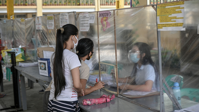 Orang tua mengumpulkan materi pembelajaran untuk anak-anak mereka di sekolah umum di Quezon City, pinggiran kota Manila, Filipina. Foto: Ted ALJIBE / AFP