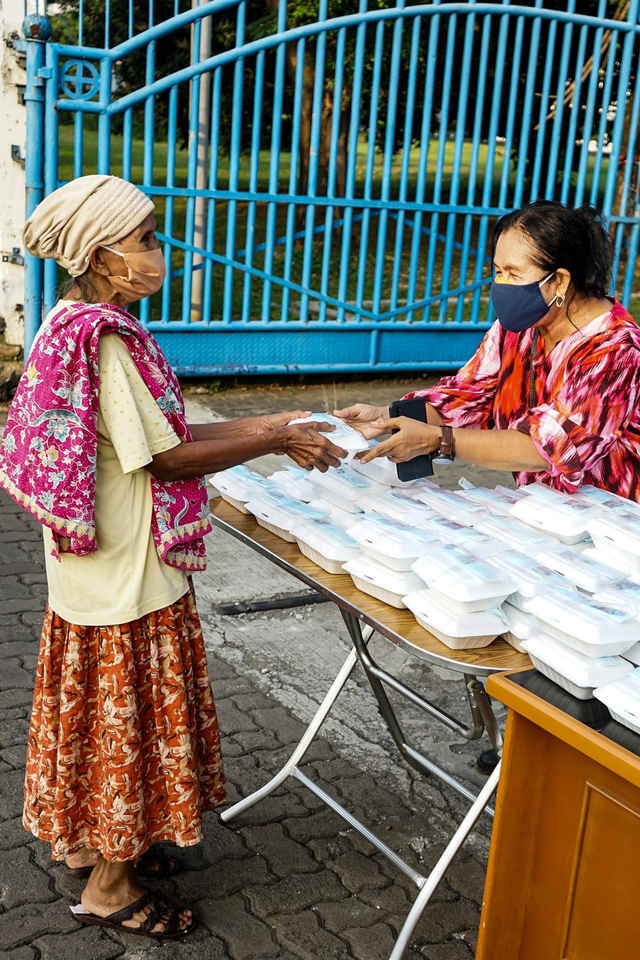 Civitas akademi Universitas Kristen Indonesia (UKI) memberikan makanan gratis kepada seorang warga di area kampus UKI Cawang, Jakarta, Kamis (18/3).  Foto: Universitas Kristen Indonesia