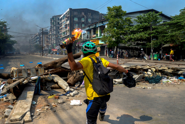 Seorang demonstran melemparkan bom molotov ke arah polisi saat mereka bergerak menuju area protes di Yangon, Myanmar. Foto: AP Photo