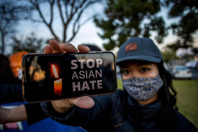 Salah satu peserta menunjukkan gambar Stop Asian Hate di ponselnya saat menggelar aksi di Garden Grove, California, Rabu (17/3). Foto: Apu Gomes/AFP