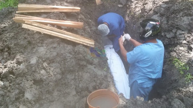 Petugas saat lakukan pemakaman mayat laki-laki laki yang ditemukan di aliran sungai Bengawan Solo Desa Sarirejo, Kecamatan Balen, Kabupaten Bojonegoro. (foto: istimewa)