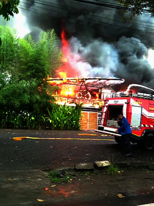 Petugas pemadam kebakaran saat mencoba memadamkan api yang membakar Warong Kobong