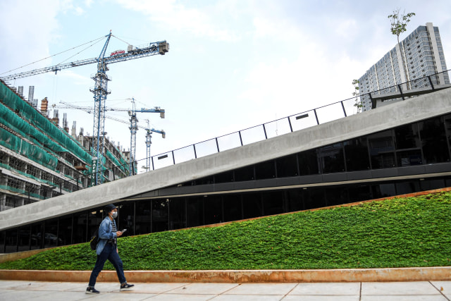 Seorang warga melintas di depan pembangunan proyek revitalisasi Taman Ismail Marzuki (TIM), Cikini, Jakarta, Senin (22/3). Foto: M Risyal Hidayat/Antara Foto