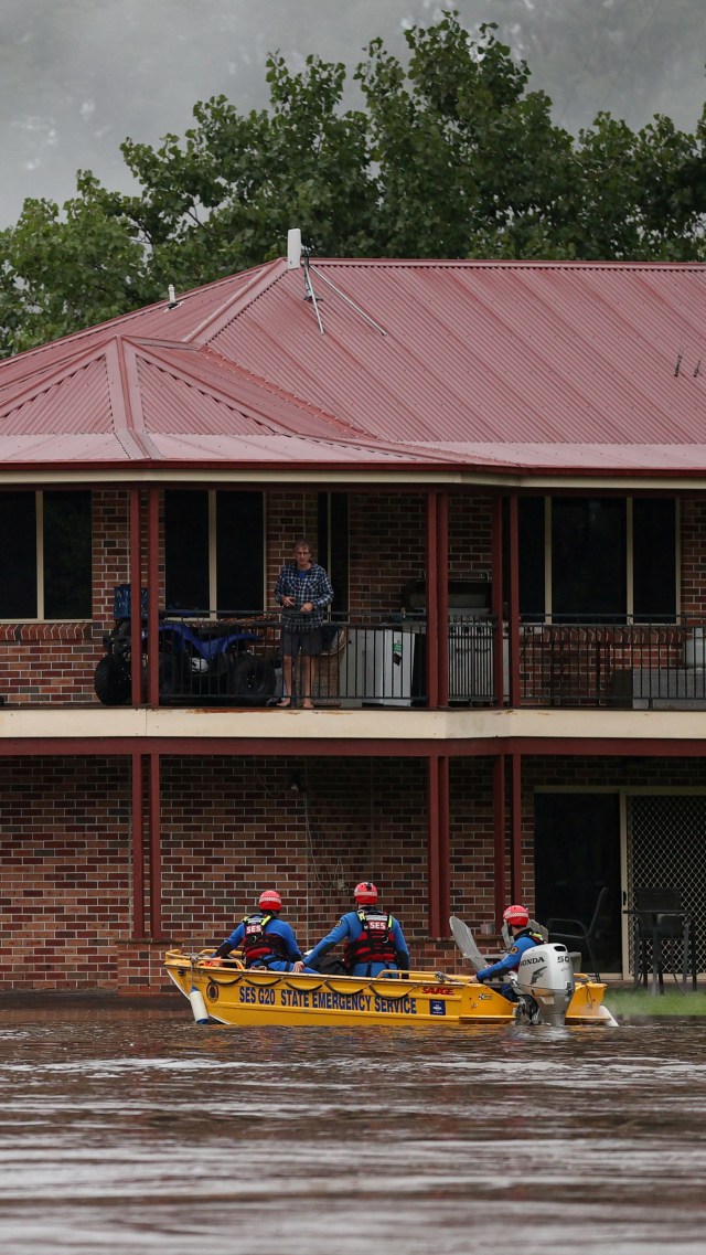 Kru penyelamat mengevakuasi warga yang terjebak di rumahnya yang terendam banjir di Sydney barat, Australia, Selasa (23/3). Foto: Loren Elliott/REUTERS