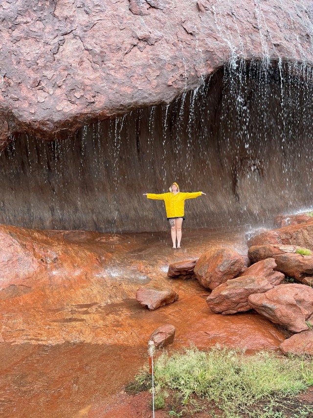Seorang wanita berpose di bawah air terjun mini di Uluru di Northern Territory, Australia. Foto: Stacey MacGregor/via REUTERS
