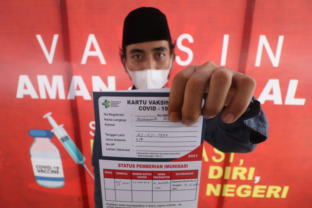 Santri memperlihatkan kartu vaksinasi usai mendapatkan suntikan vaksin COVID-19 AstraZeneca di Pondok Pesantren Lirboyo, Kota Kediri, Jawa Timur. Foto: Prasetia Fauzani/Antara Foto