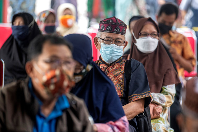 Sejumlah jemaah calon haji antre mengikuti vaksinasi COVID-19 dosis pertama di Puskesmas Merdeka, Palembang, Sumatera Selatan, Kamis (25/3). Foto: Nova Wahyudi/Antara Foto
