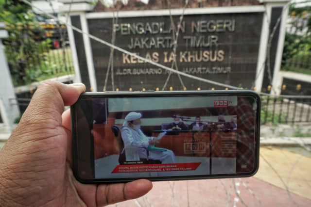 Awak media menyiarkan siaran langsung Habib Rizieq di depan PN Jaktim setelah polisi melarang masuk wartawan untuk meliput. Foto: Jamal Ramadhan/kumparan