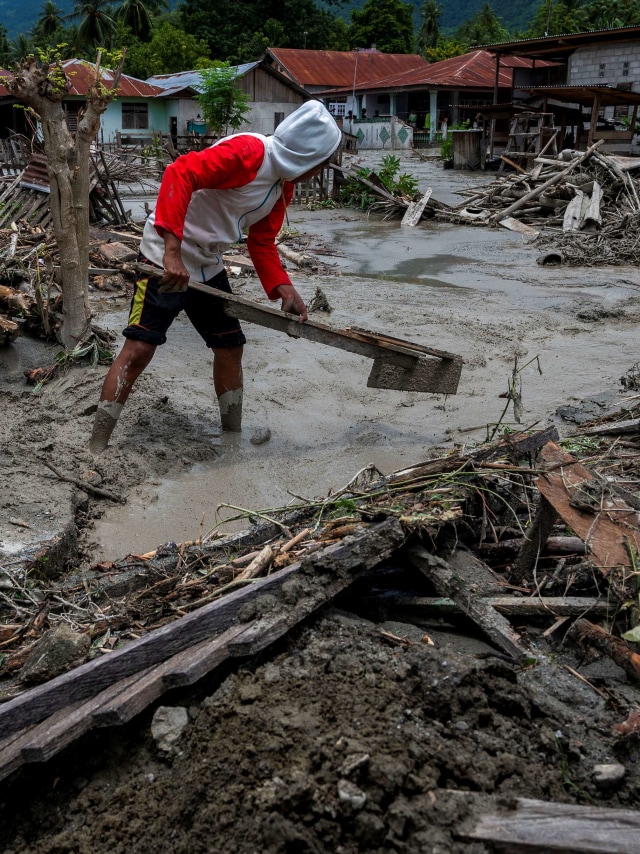 Sejumlah warga membersihkan sisa lumpur yang menerjang rumahnya di Desa Beka, Marawola, Kabupaten Sigi, Sulawesi Tengah, Sabtu (27/3). Foto: Basri Marzuki/Antara Foto