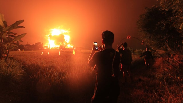 Warga mengambil video dengan gawai miliknya saat terjadi kebakaran di kompleks Pertamina RU VI Balongan, Indramayu, Jawa Barat, Senin (29/3/2021) dini hari. Foto: Dedhez Anggara/ANTARA FOTO