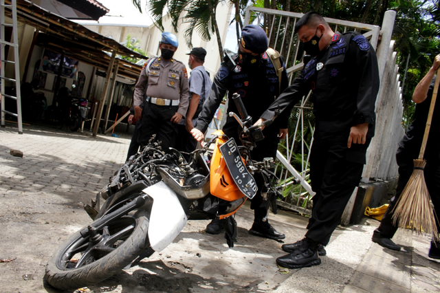 Anggota polisi mengamati motor yang digunakan terduga pelaku bom bunuh diri sebelum dievakuasi di depan Gereja Katedral Makassar, Sulawesi Selatan, Senin (29/3/2021). Foto: Arnas Padda/ANTARA FOTO