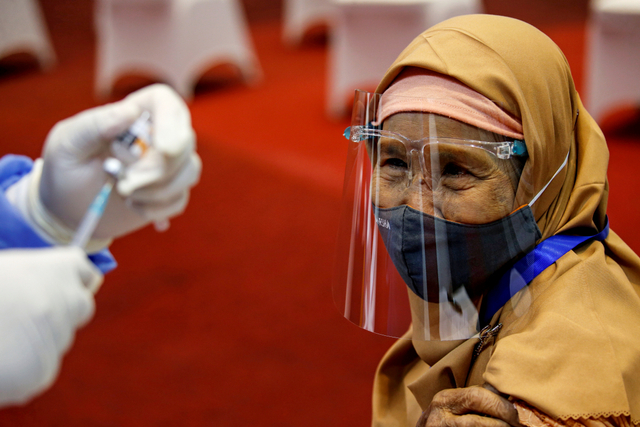 Seorang wanita bersiap untuk menerima suntikan vaksin corona Sinovac, selama program vaksinasi massal di Bursa Efek Indonesia di Jakarta, Rabu (31/3). Foto: Willy Kurniawan/REUTERS