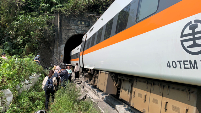 Orang-orang berjalan di samping kereta yang tergelincir di terowongan di utara Hualien, Taiwan, Jumat (2/4). Foto: Taiwan's National Fire Agency/Handout via REUTERS