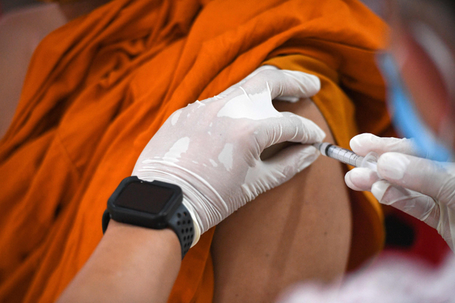 Biksu Buddha menerima dosis vaksin virus corona di sebuah kuil di Bangkok, Thailand. Foto: Chalinee Thirasupa/Reuters