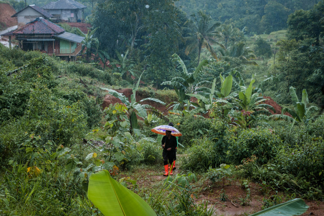 Seorang warga berjalan di sekitar rumah yang telah tertimbun tanah di Desa Banjarsari, Lebak, Banten. Foto: Muhammad Bagus Khoirunas/ANTARA FOTO