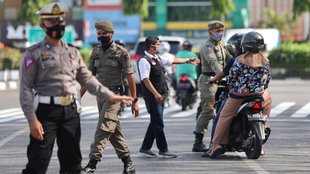 Petugas gabungan menghentikan pengendara motor yang tidak memakai masker pada razia protokol kesehatan di alan depan Masjid Raya Baiturrahman, Banda Aceh, Jumat (12/3). Foto: Suparta/acehkini