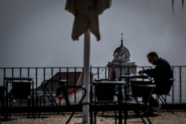 Seorang pria duduk di teras kafe di sudut pandang Portas do Sol di Lisbon, Portugal. Foto: PATRICIA DE MELO MOREIRA/AFP