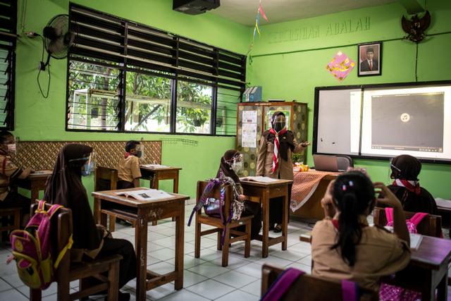 Guru (tengah) memberikan materi pelajaran kepada murid saat uji coba pembelajaran tatap muka pada hari pertama di SD Negeri Kenari 08 Pagi, Jakarta, Rabu (7/4).  Foto: Aprillio Akbar/ANTARA FOTO