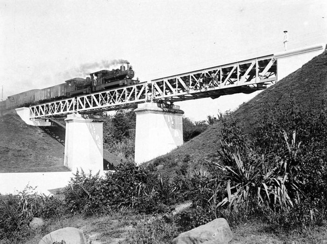 Kereta pada masa kolonial Belanda. (A Dutch East Indian Railway Company steam train crosses a railway bridge over the Code River. Wikipedia).