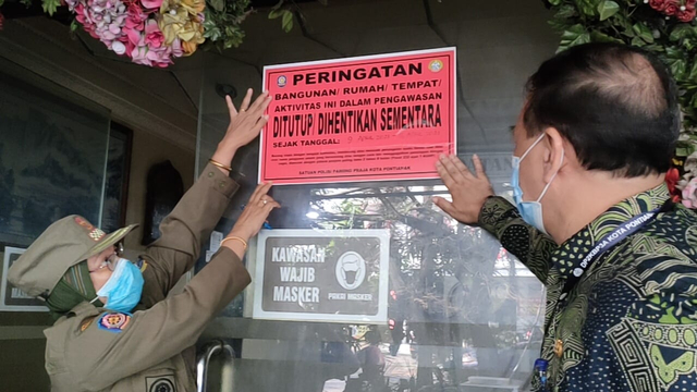 Kasat Pol PP Kota Pontianak, Syarifah Adriana, menempelkan kertas segel di pintu sebuah penginapan di Pontianak. Foto: Dok Hi!Pontianak