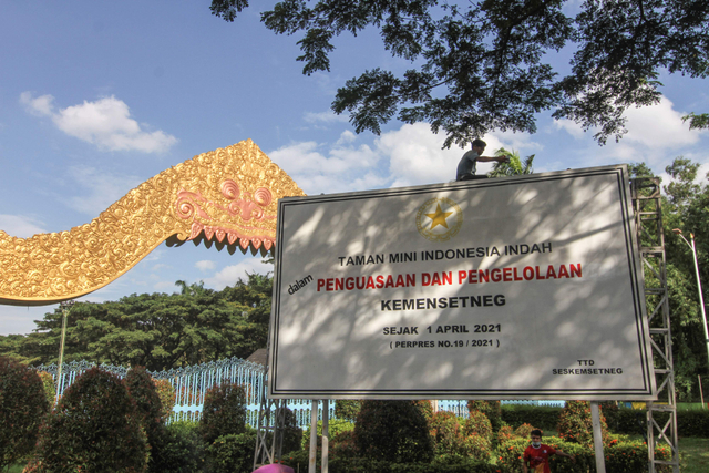 Pekerja memasang pelang bertuliskan TMII dalam penguasaan dan pengelolaan Kemensetneg di depan gerbang TMII, Jakarta, Rabu (7/4). Foto: Asprilla Dwi Adha/Antara Foto